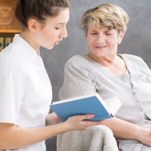 A home nuse reading to a patient.